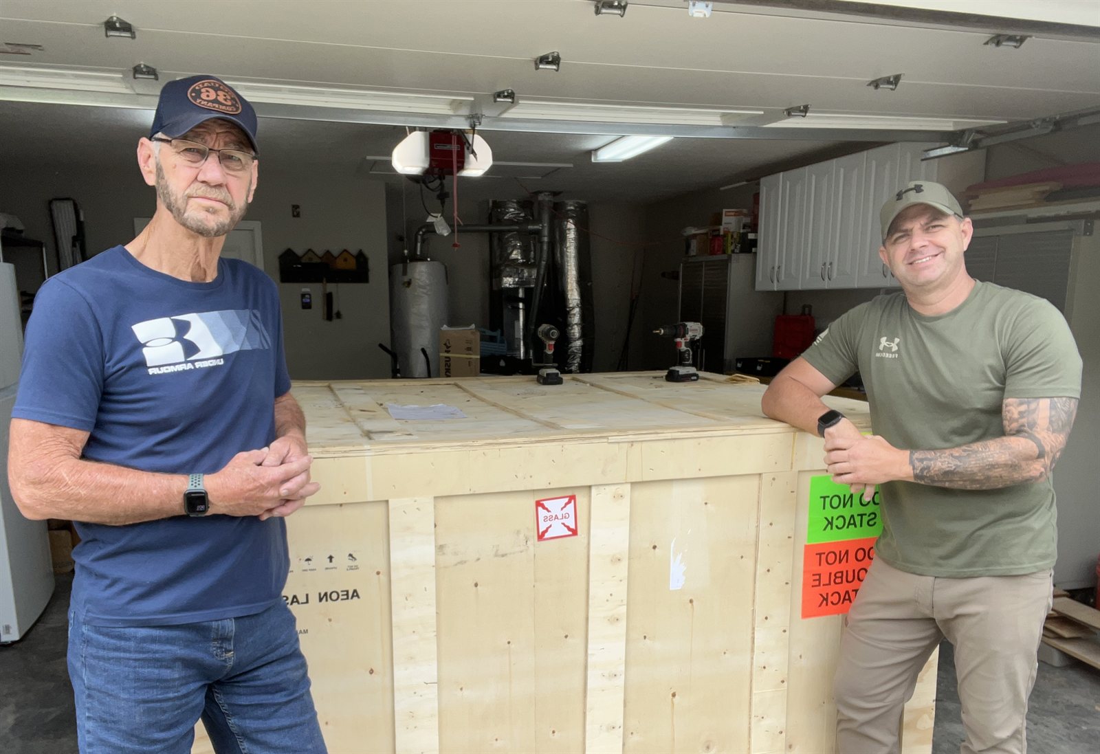 David and Brian Graham together in the shop, standing next to their new laser equipment