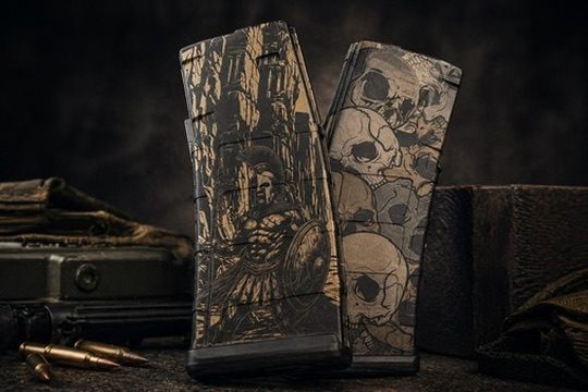 Two custom engraved PMAG rifle magazines — one with Spartan warrior artwork, one with memento-mori skull design